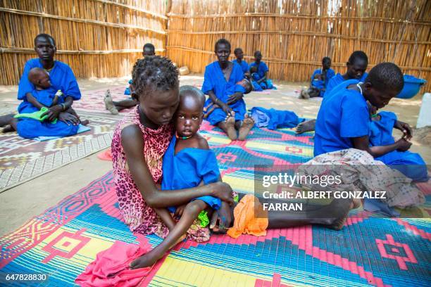 Two women hold their acute malnourished children on March 4 in a stabilisation centre in Ganyiel, Panyijiar county, in South Sudan. South Sudan was...