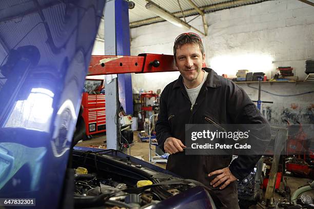 mechanic stood with car in garage - sole proprietorship stock pictures, royalty-free photos & images