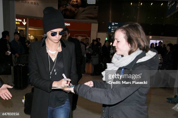 Cara Delevingne signs autographs as she arrives at Charles-de-Gaulle airport on March 4, 2017 in Paris, France.