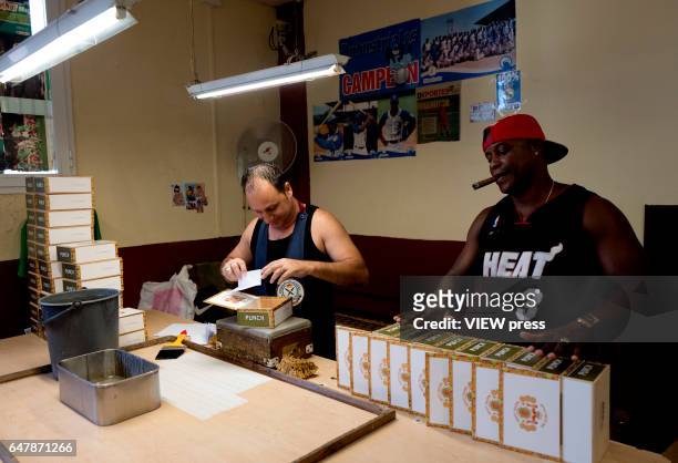 Man smokes a cigar as they select them to pack at La Corona cigar factory on March 01, 2017 in Havana, Cuba. Tourists from around the world visit...