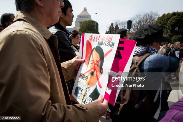 Anti-Abe protester holding a placard reading &quot;GET OUT! IDIOT PM ABE, BRING BACK OUR PREVIOUS JAPAN! gather in front of the National Diet...