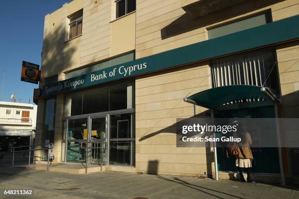 Woman stands at an ATM cash machine outside a local branch of Bank of Cyprus on March 5, 2017 in Nicosia, Cyprus. Several U.S. Democratic senators...