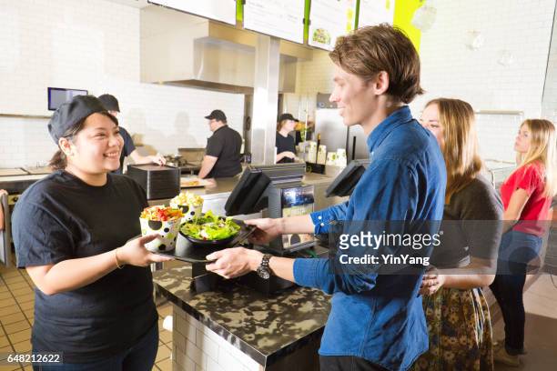 kitchen and wait staff serving customers in fast food restaurant - fast food stock pictures, royalty-free photos & images