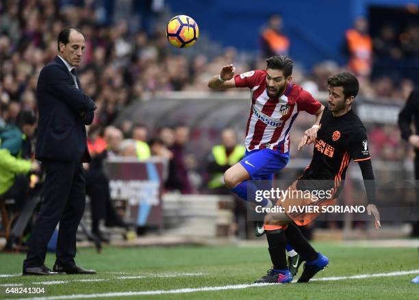 Atletico Madrid's Belgian midfielder Yannick Ferreira Carrasco vies with Valencia's defender Jose Gaya under the eyes of Valencia's coach Voro...