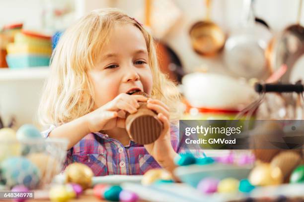 kleine mädchen essen schokolade osterhasen - chocolate bunny stock-fotos und bilder