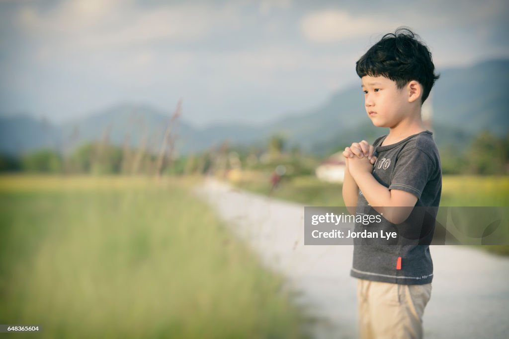 Little boy praying outdoor