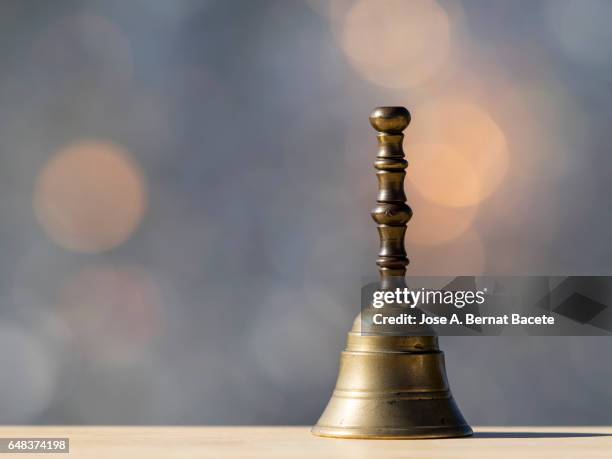 hand small bell of metallic hand, on a table of wood illuminated by the light of the sun - purperwinde stockfoto's en -beelden