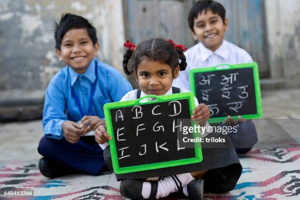 little school children in uniform holding slate - clapperboard stock pictures, royalty-free photos & images