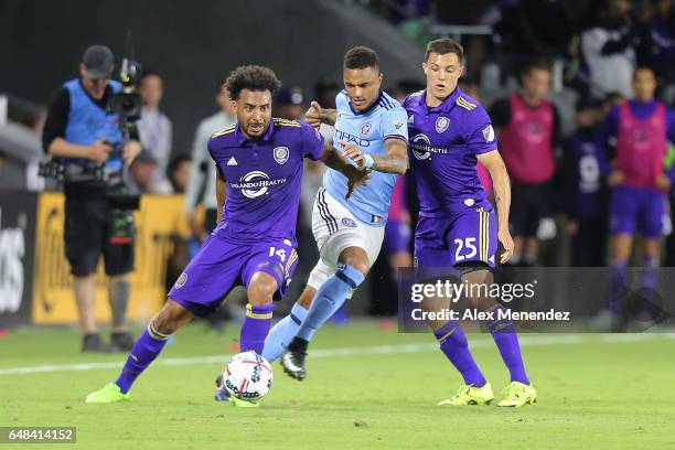 Giles Barnes of Orlando City SC dribbles the ball past Sean Okoli of New York City FC and Donny Toia of Orlando City SC during a MLS soccer match...
