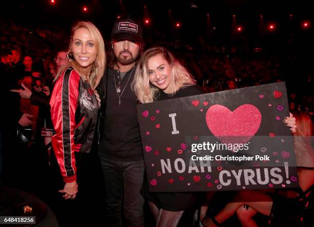 Tish Cyrus, and singers-songwriters Billy Ray Cyrus and Miley Cyrus pose with a sign reading 'I heart Noah Cyrus' during the 2017 iHeartRadio Music...