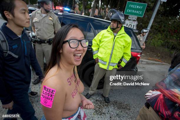 Anni Ma passes police officers as she marches topless for the right of women to decide for themselves what they do with their bodies during the...