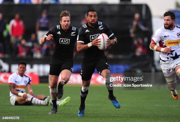 New Zealand player Sione Molia scores a try against the United States while teammate Tim Mikkelson, left, bleeds from the mouth during their sevens...