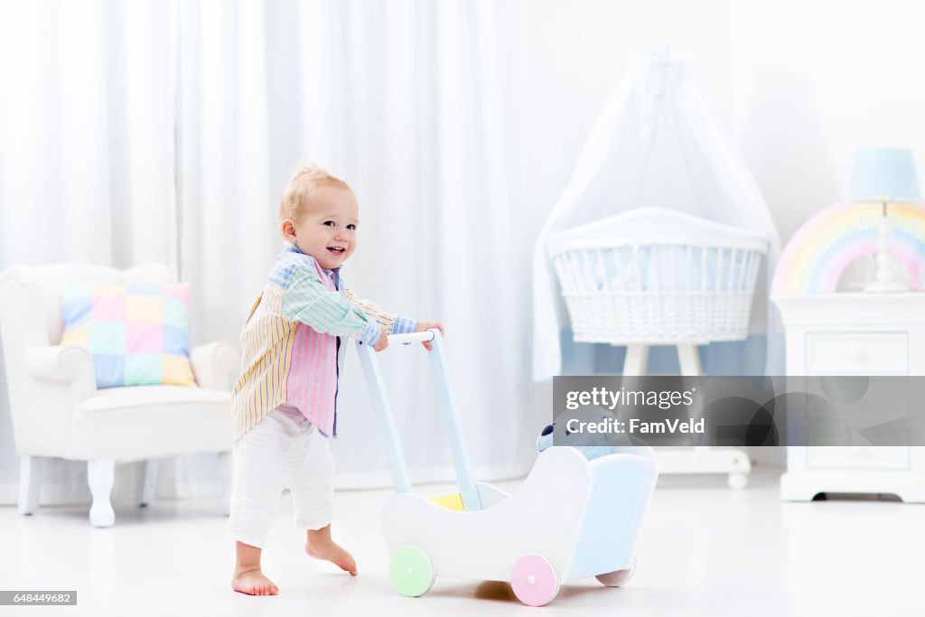 Baby with push walker in white bedroom