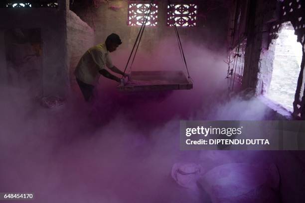 An Indian labourer sifts coloured powder, known as 'gulal', to be used during the forthcoming spring festival of Holi, inside a factory at Fulbari...