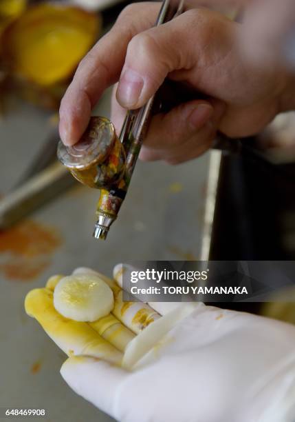 This picture taken on January 18, 2017 shows a craftswoman of Fake Food Hatanaka making plastic banana earrings at the company's studio in...