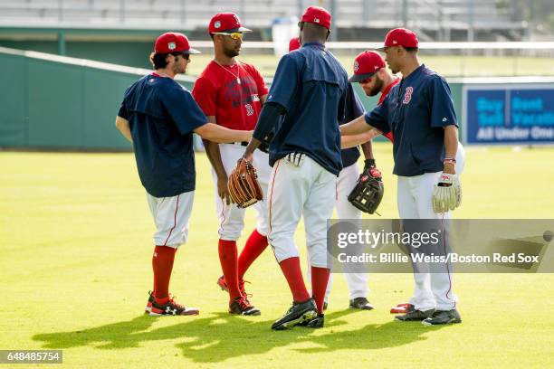 Mookie Betts of the Boston Red Sox huddles with Andrew Benintendi, Chris Young, and other outfielders before a Spring Training game against the Tampa...