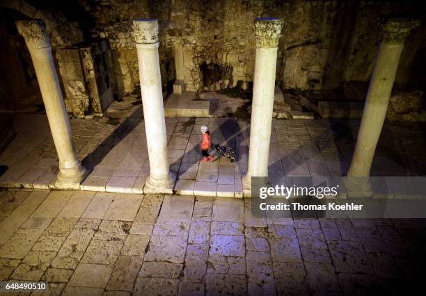 Jerusalem, Israel A girl runs with a trolley through the remains of a temple in the Jewish Quarter, historic city center of Jerusalem on February 08,...