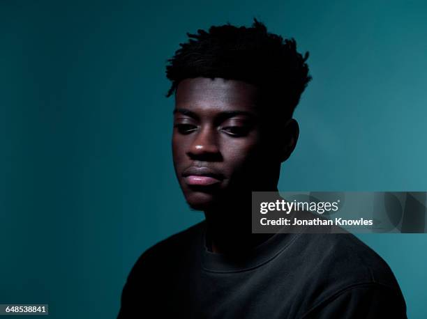 dark skinned male,looking down, blurry - self doubt ストックフォトと画像