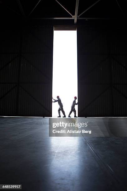 two men pushing open doors - industrial door stock pictures, royalty-free photos & images