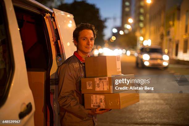 courier delivering parcels and boxes - working late foto e immagini stock