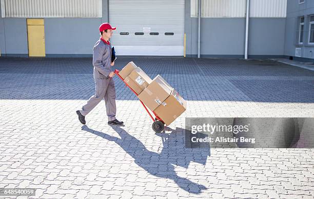 courier delivering parcels and boxes - spingere carrello foto e immagini stock