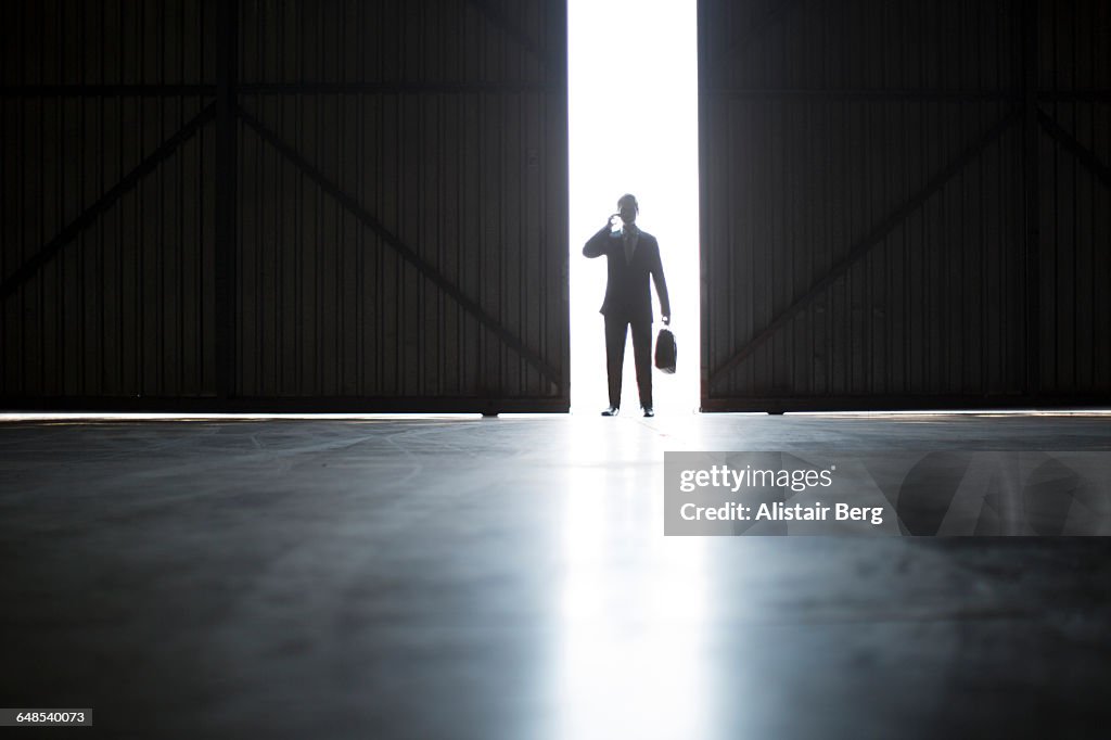 Businessman on phone in warehouse doorway