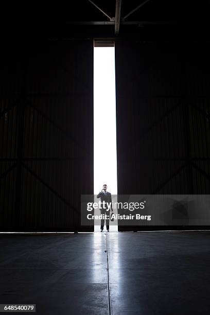 businessman on phone in warehouse doorway - door hanger stock pictures, royalty-free photos & images