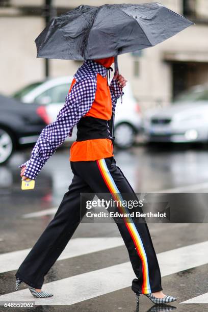 Fashion blogger Miu wears an orange hoodie sweater with blue and white checked sleves and collar, a black large belt, and black sportswear pants with...