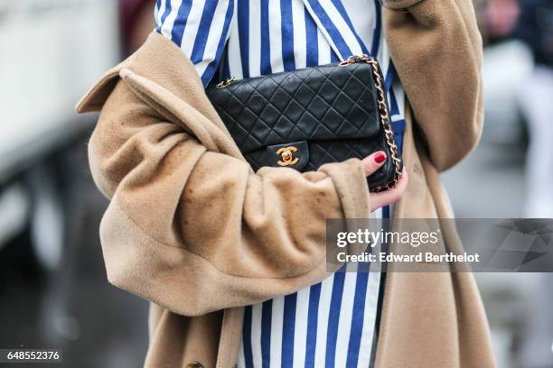 Guest wears a beret hat, a striped jacket, striped skirt, a white turtleneck top, a beige coat, a Chanel bag, and yellow heels, outside the Valentino...