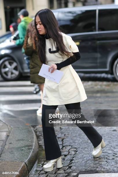 Guest wears a white dress, and black flared pants, and white platform shoes, outside the Valentino show, during Paris Fashion Week Womenswear...