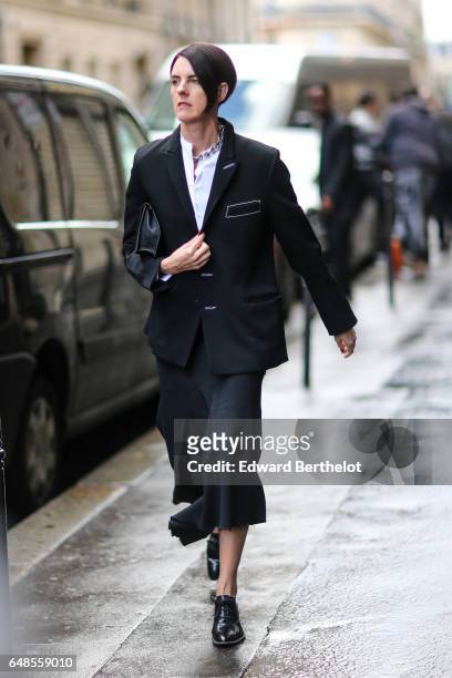 Guest wears a white shirt, a black jacket, a black skirt, and black leather shoes, outside the Valentino show, during Paris Fashion Week Womenswear...