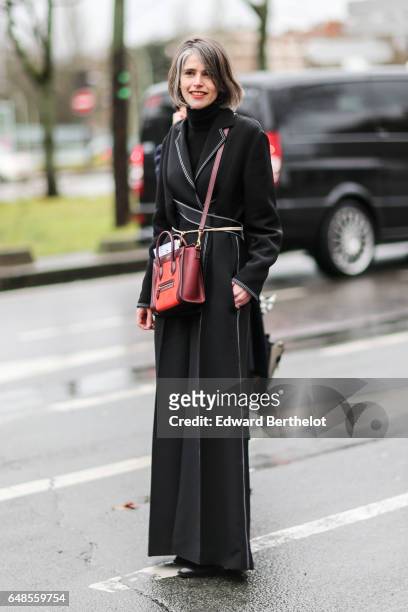 Guest wears a black dress, a black turtleneck, and a red bag, outside the Celine show, during Paris Fashion Week Womenswear Fall/Winter 2017/2018, on...
