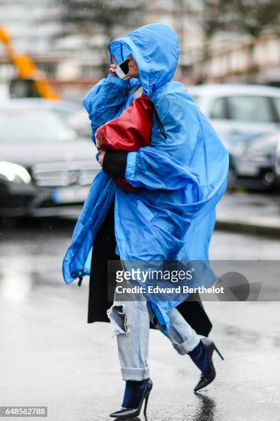 Guest wears a blue raincoat, and a red leather bag, outside the Celine show, during Paris Fashion Week Womenswear Fall/Winter 2017/2018, on March 5,...