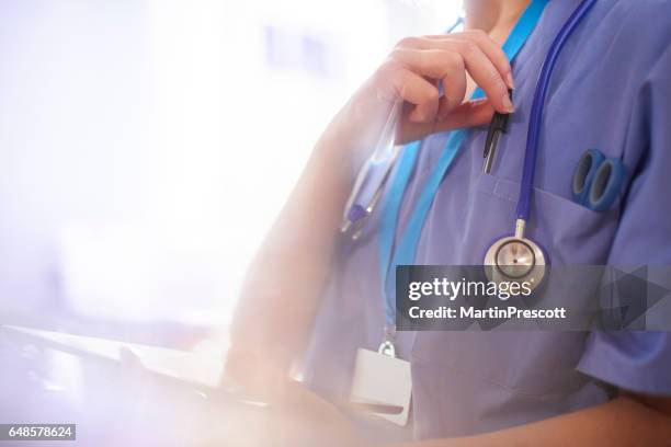 chirurg met behulp van digitale tablet in het ziekenhuis en het bereiken van haar pen - doctor uniform stockfoto's en -beelden