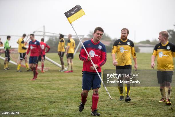 Garrison Gunners Jago Lethbridge carries the corner flag at the end of the match between the Garrison Gunners and Woolpack Wanderers at the Garrison...