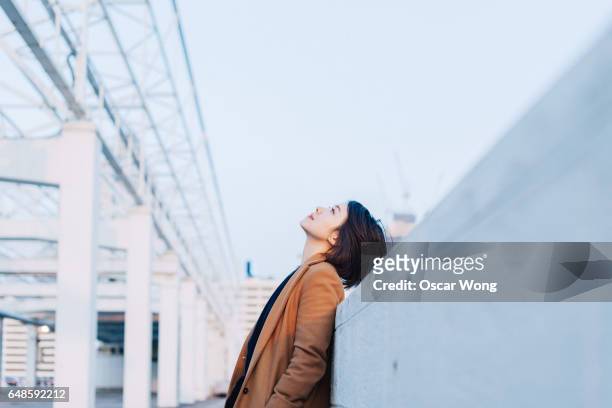 beautiful woman looking up at outdoor car park - sognare ad occhi aperti foto e immagini stock