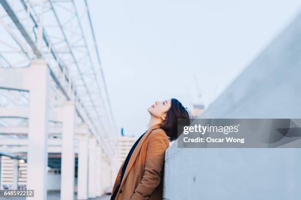 beautiful woman looking up at outdoor car park - asian woman dream stockfoto's en -beelden