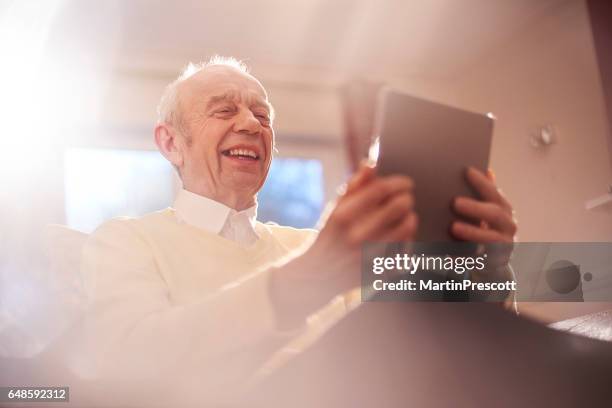 senior man laughing at digital tablet - widower stock pictures, royalty-free photos & images