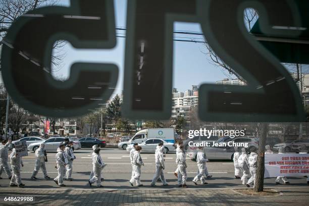 Families of victims of occupational diseases and activists march in front of Samsung Electronics' Suwon Headquarters as they hold 79 portraits of...