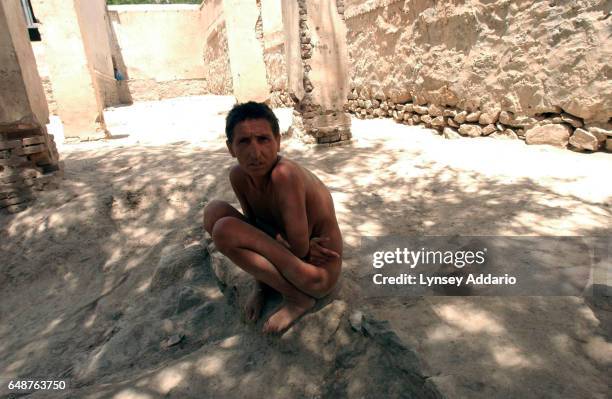 An Afghan woman squats naked outside the women's ward of Kabul's only psychiatric hospital, in Kabul, Afghanistan on July 23, 2002. After two...
