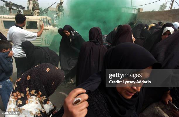 Iraqi Women scramble for cover as American soldiers from the First Cavalry Division fire gas onto a desperate crowd during a propane distribution in...