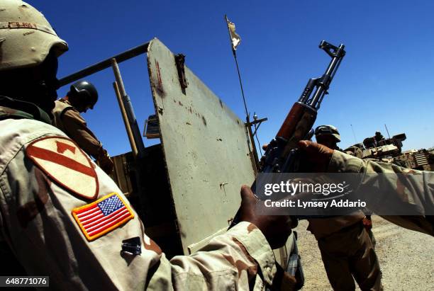 Troops disarm a truck of soldiers with the Mujahedeen Khalq Organization, M.K.O., as they pass through an impromptu U.S. Checkpoint in Baghdad, Iraq,...