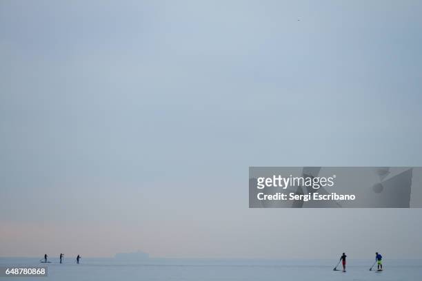 people practicing stand up paddleboarding (sup) in calm waters of the mediterranean sea - barceloneta beach bildbanksfoton och bilder