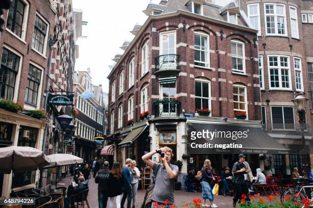 young man makes a photo in front of lunchroom de drie grafjes in amsterdam, netherlands - drie personen stock-fotos und bilder