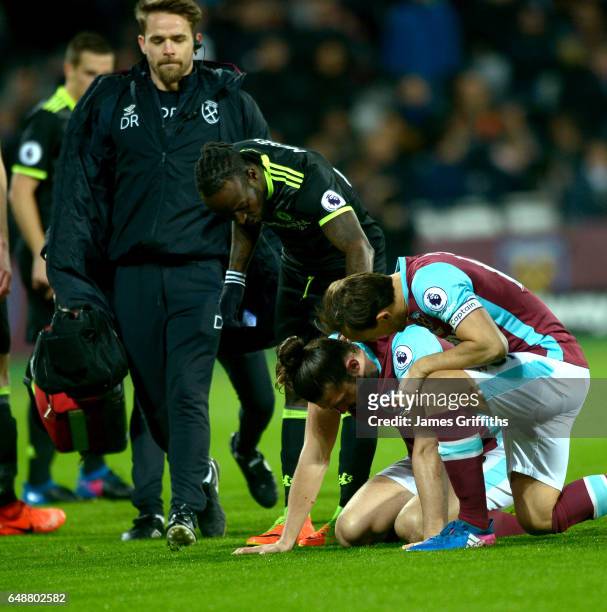 Andy Carroll of West Ham United is checked upon by former team mate Victor Moses of Chelsea and Mark Noble during the Premier League match between...