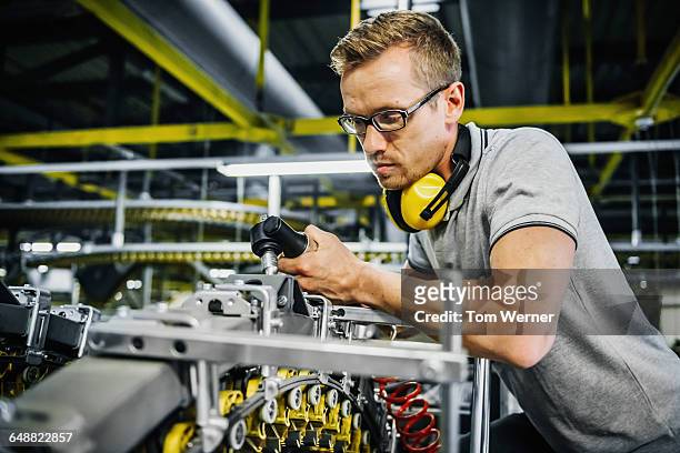worker with tool repairing a large conveyor - paper industry stock-fotos und bilder