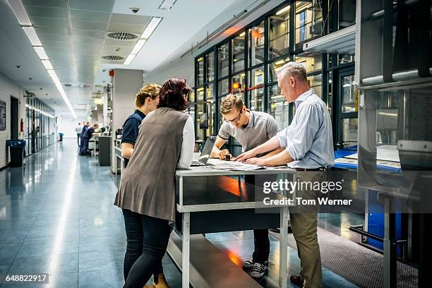 staff meeting close to a production line - team industrie stockfoto's en -beelden