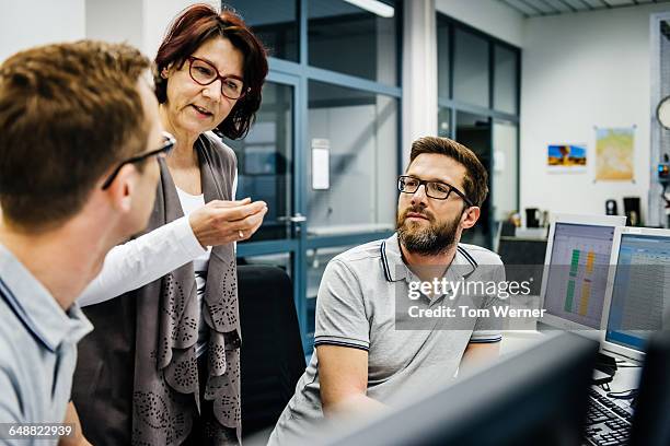 businesswoman guiding engineers in a control room - sala di controllo foto e immagini stock