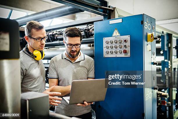 two engineers with laptop in large printery - paper industry stock-fotos und bilder