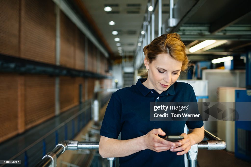 Female worker in a factory checking smart phone